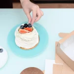 کاپ‌کیک تک‌نفره تزئین شده، کنار جعبه مقوایی کوچک بیرون‌بر